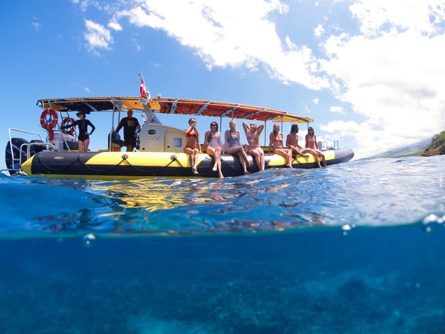 half underwater photo of guests sitting on the side of the boat